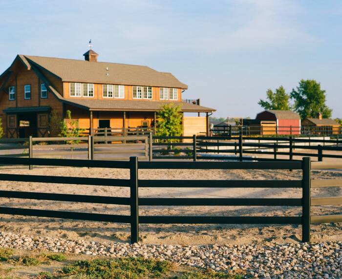 Black steel fence with equestrian barn